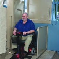 man riding a scooter exiting a Bruno 3100 outdoor vertical platform lift
