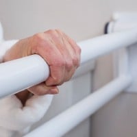up close view of hand gripping wall mounted safety rail for toilet