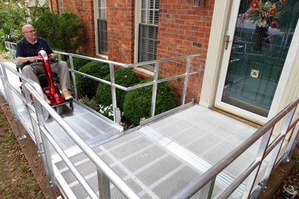 man riding scooter on aluminum ramp to safely access the front entrance of his home