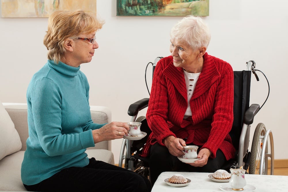 woman eating lunch at home with senior mother in wheelchair